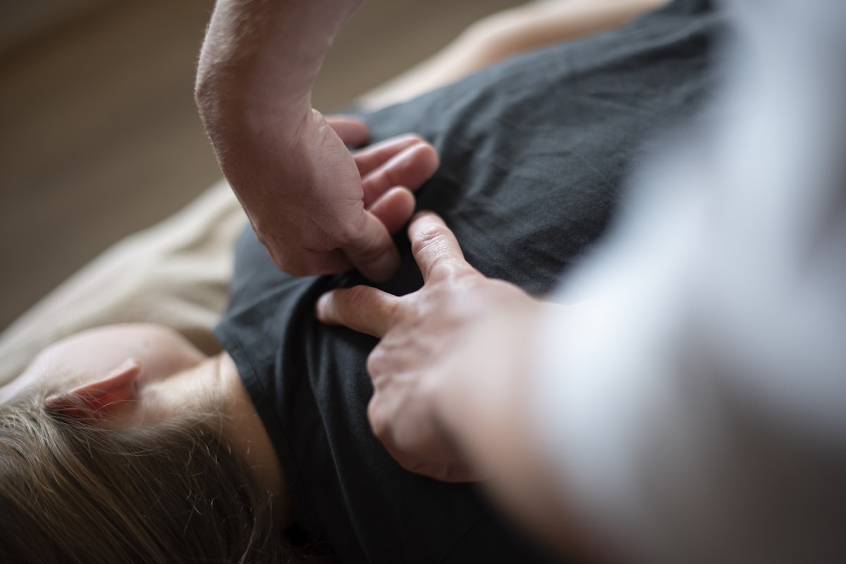 Therapeut behandelt die Schulter eines liegenden Patienten